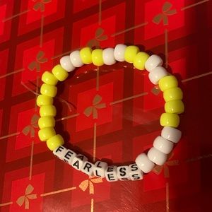 A Taylor swift bracelet yellow and white with letters that say fearless